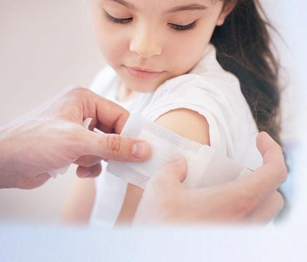 young girl getting a band aid on her arm